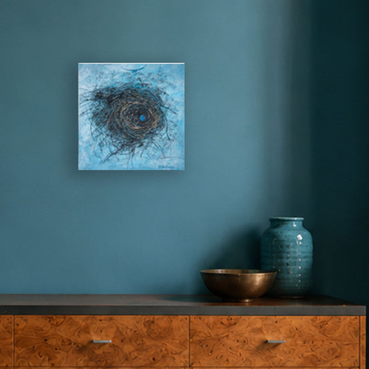 A square abstract wall art print depicting a nest circular composition in blue, brown, and black tones, displayed on a teal wall above a wooden console with a bowl and vase.