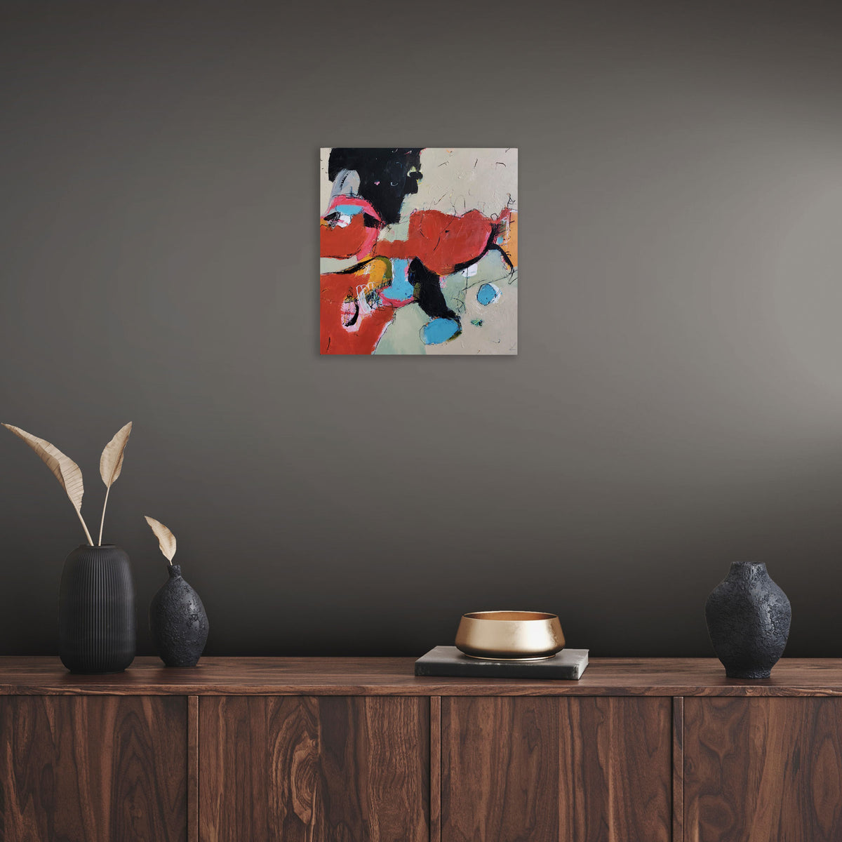 Abstract painting titled Pigments by Karen Hammat displayed on a dark grey wall above a wooden sideboard in a contemporary interior.