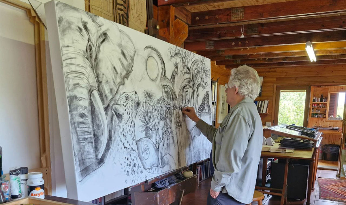 South African artist Hein Botha working on a large-scale charcoal drawing in his studio, surrounded by drawing tables and art materials.