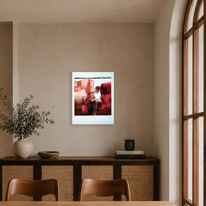 A framed abstract watercolour with red, pink, and white geometric shapes hangs on a beige wall in a contemporary dining room setting.