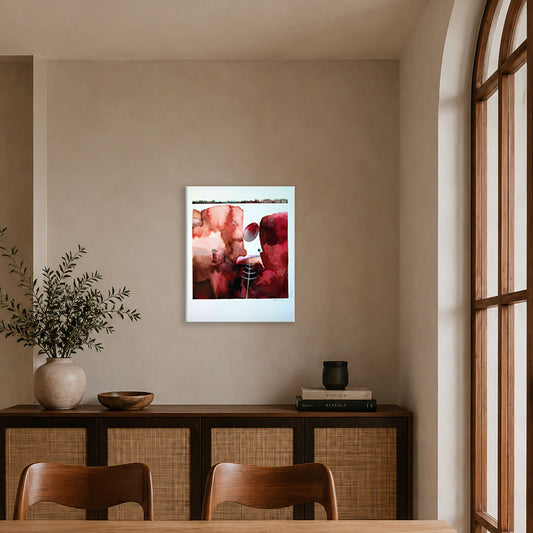 A framed abstract watercolour with red, pink, and white geometric shapes hangs on a beige wall in a contemporary dining room setting.
