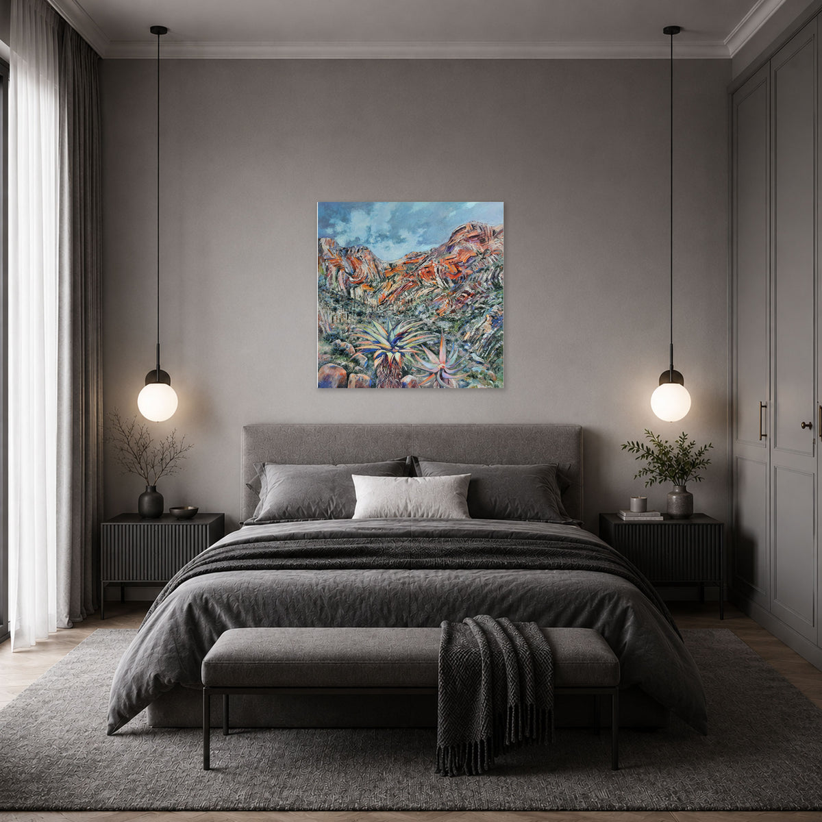 A modern bedroom with a gray upholstered bed, matching bench, pendant lights, and a colorful abstract landscape painting by Hein Botha centered on the gray wall above the bed.