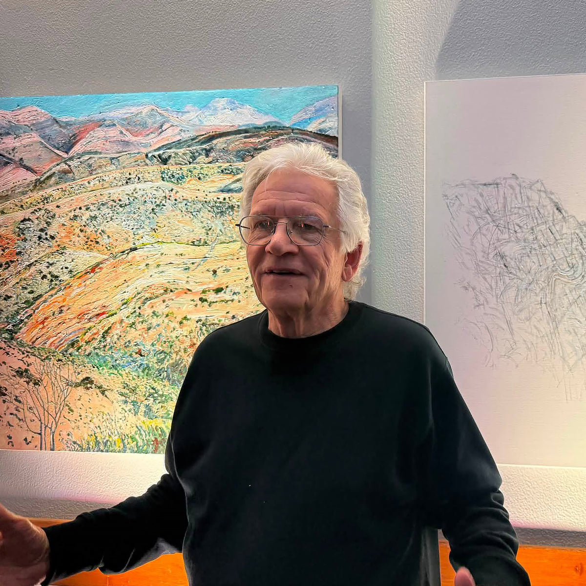 South African artist Hein Botha standing in front of two of his large-scale artworks at an exhibition.