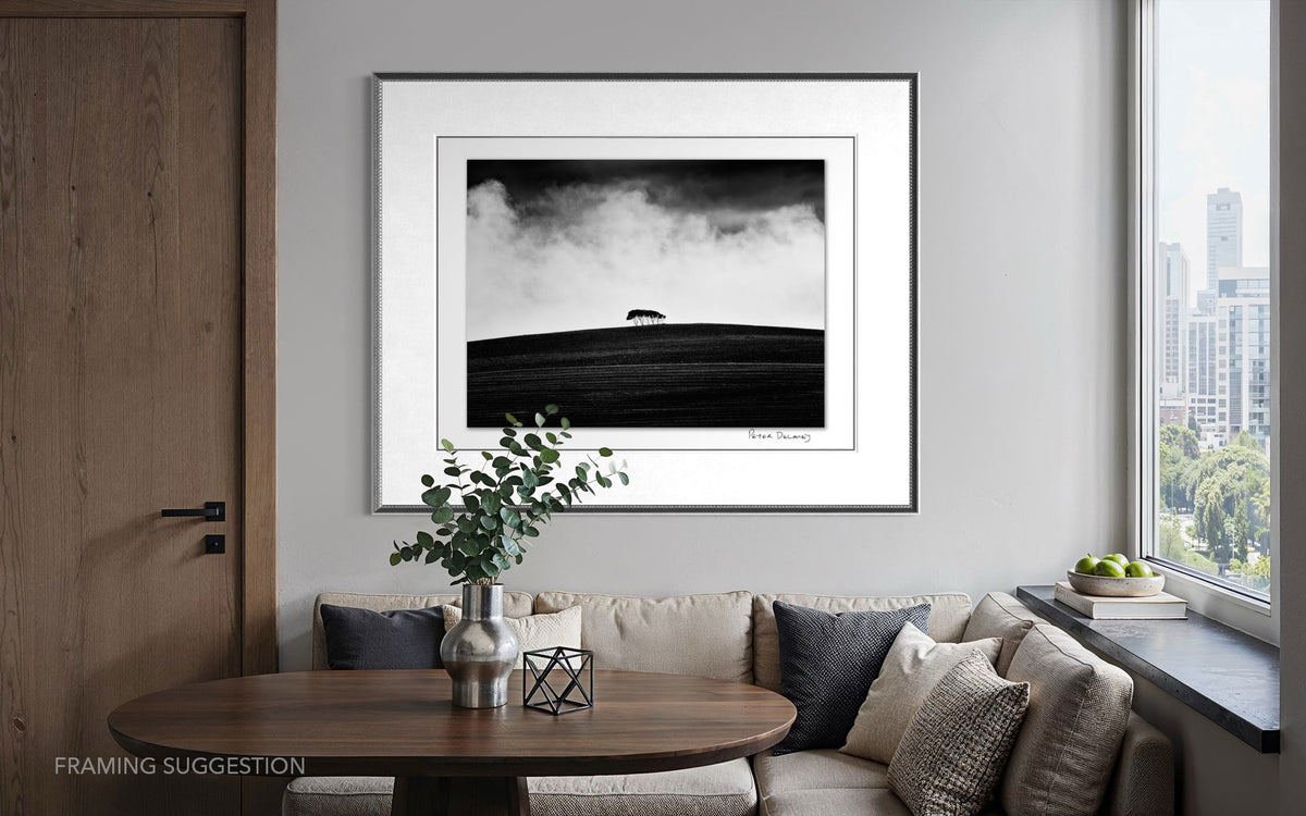 Peter Delaney’s Kareno: The Withered Field framed above a dining nook in a modern apartment, showing the black and white landscape photograph in an interior setting.