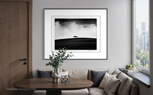 Peter Delaney’s Kareno: The Withered Field framed above a dining nook in a modern apartment, showing the black and white landscape photograph in an interior setting.