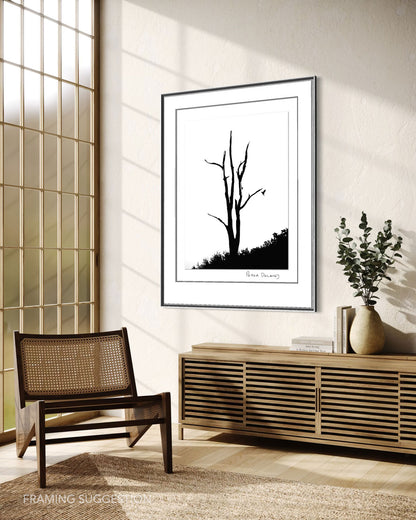 Peter Delaney’s Zanshin black and white fine art photograph framed above a wooden sideboard in a warm, contemporary interior with a cane chair.