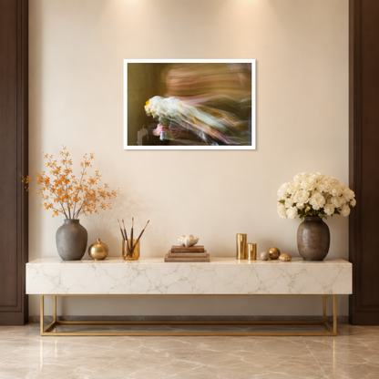 A framed abstract art print hangs on a beige wall above a marble console table decorated with vases, gold accents, and books. The print features a soft, blurred composition with flowing tones of white, gold, and dark brown.