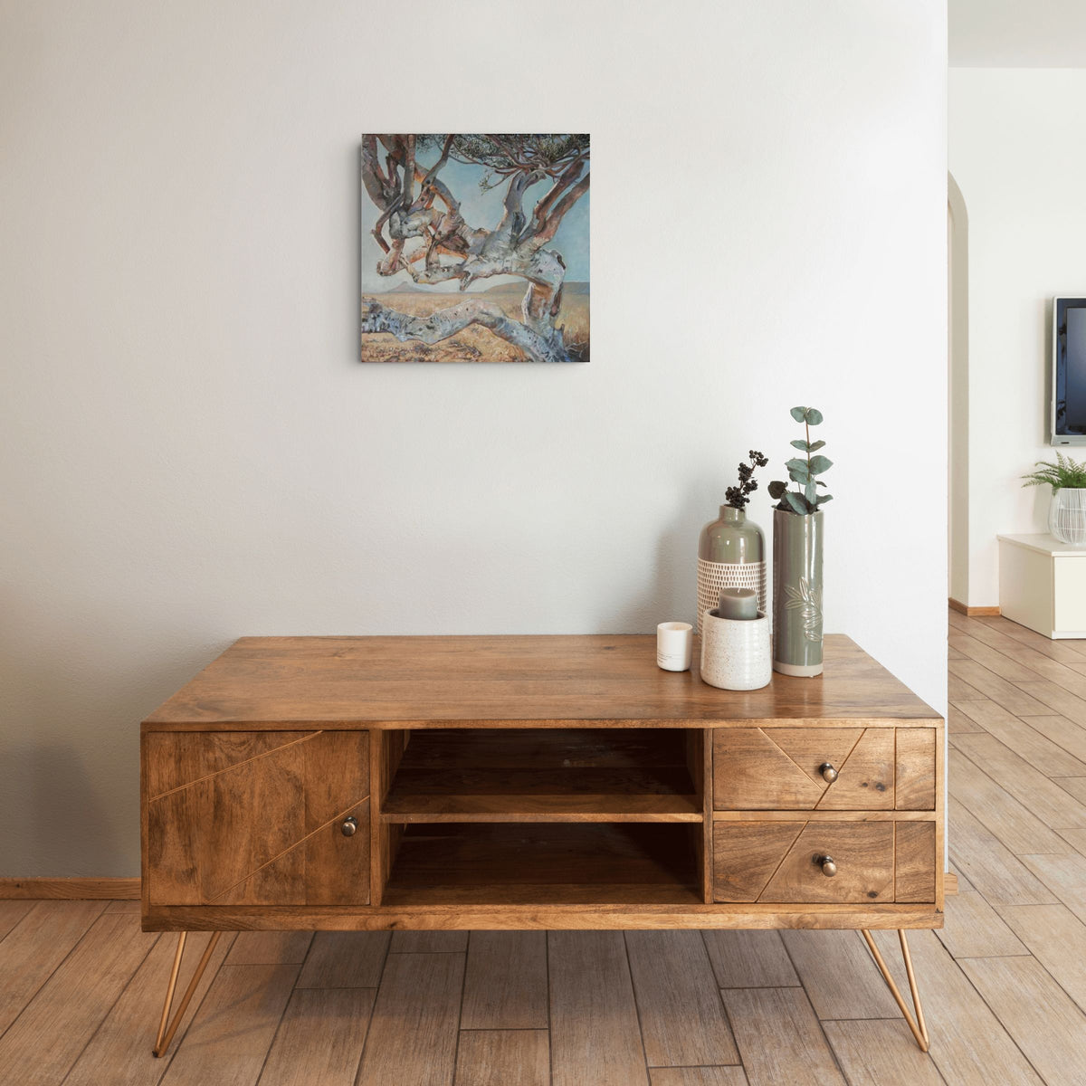 Shepherd Tree Tango by Hein Botha, acrylic landscape painting displayed above a wooden cabinet in a contemporary neutral interior.