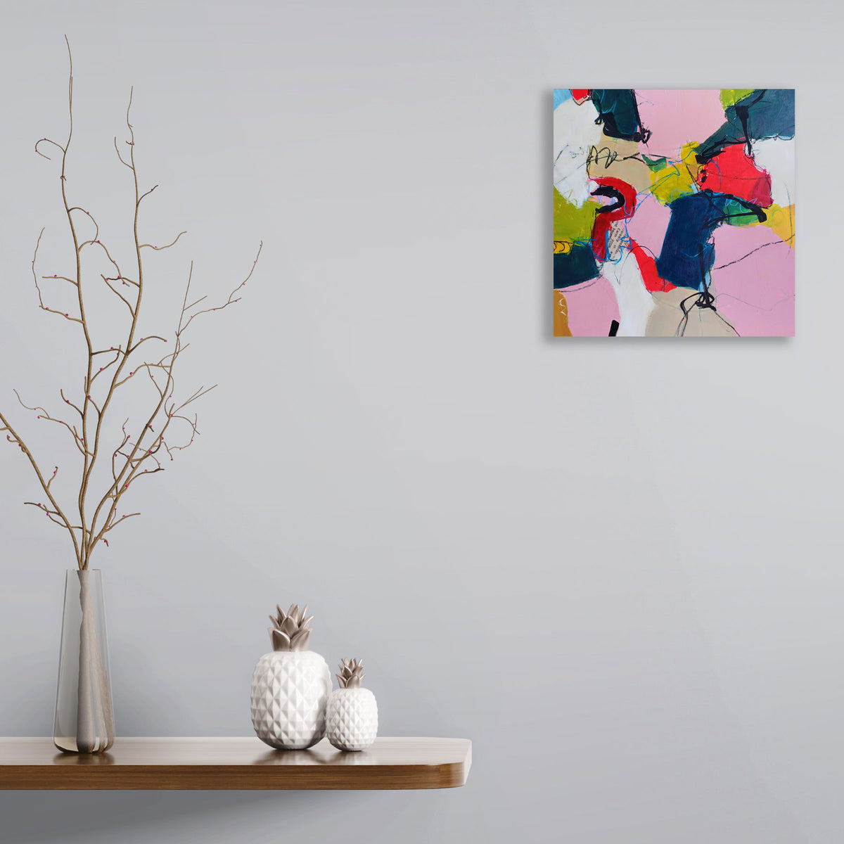 Unexpected by Karen Hammat displayed on a pale grey wall above a wooden shelf with decorative ceramics and branches.