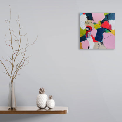 Unexpected by Karen Hammat displayed on a pale grey wall above a wooden shelf with decorative ceramics and branches.
