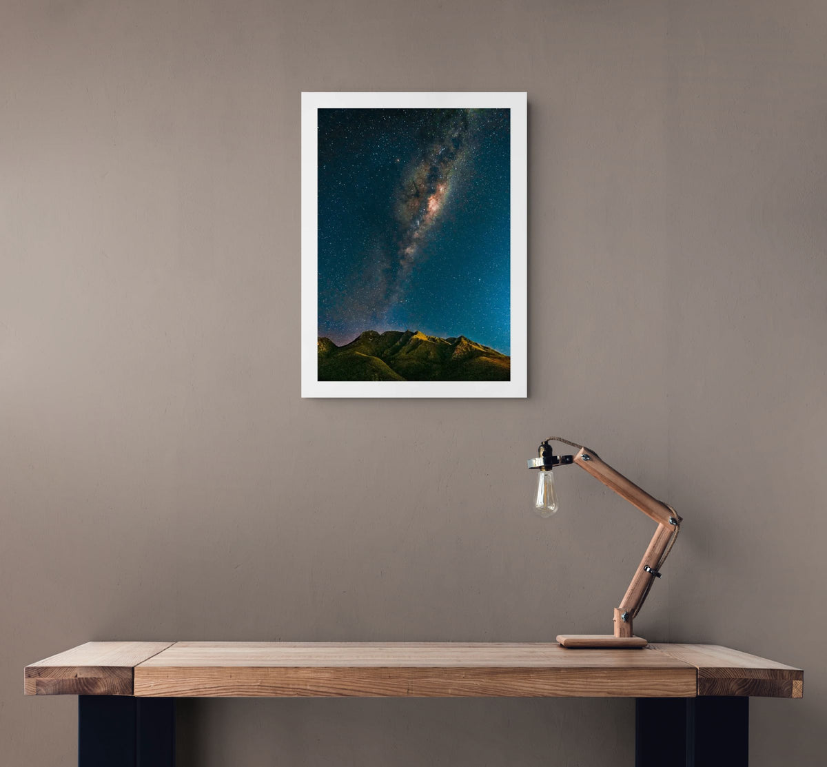Milky Way Over the Outeniquas by Chris Daly, South African landscape and astrophotography print displayed above a wooden desk in a contemporary interior.