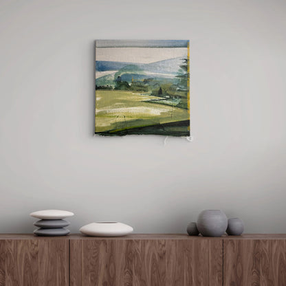 An abstract landscape painting in muted green, blue, and gray tones, displayed on a light gray wall above a wooden sideboard with decorative ceramic vases.